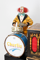 Charlie mit seiner Schlagzeugbatterie wird von einer Drehorgel begleitet.